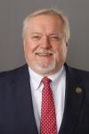 White man with black suit, white shirt and red tie