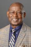 Black man in grey suite with blue shirt and striped tie