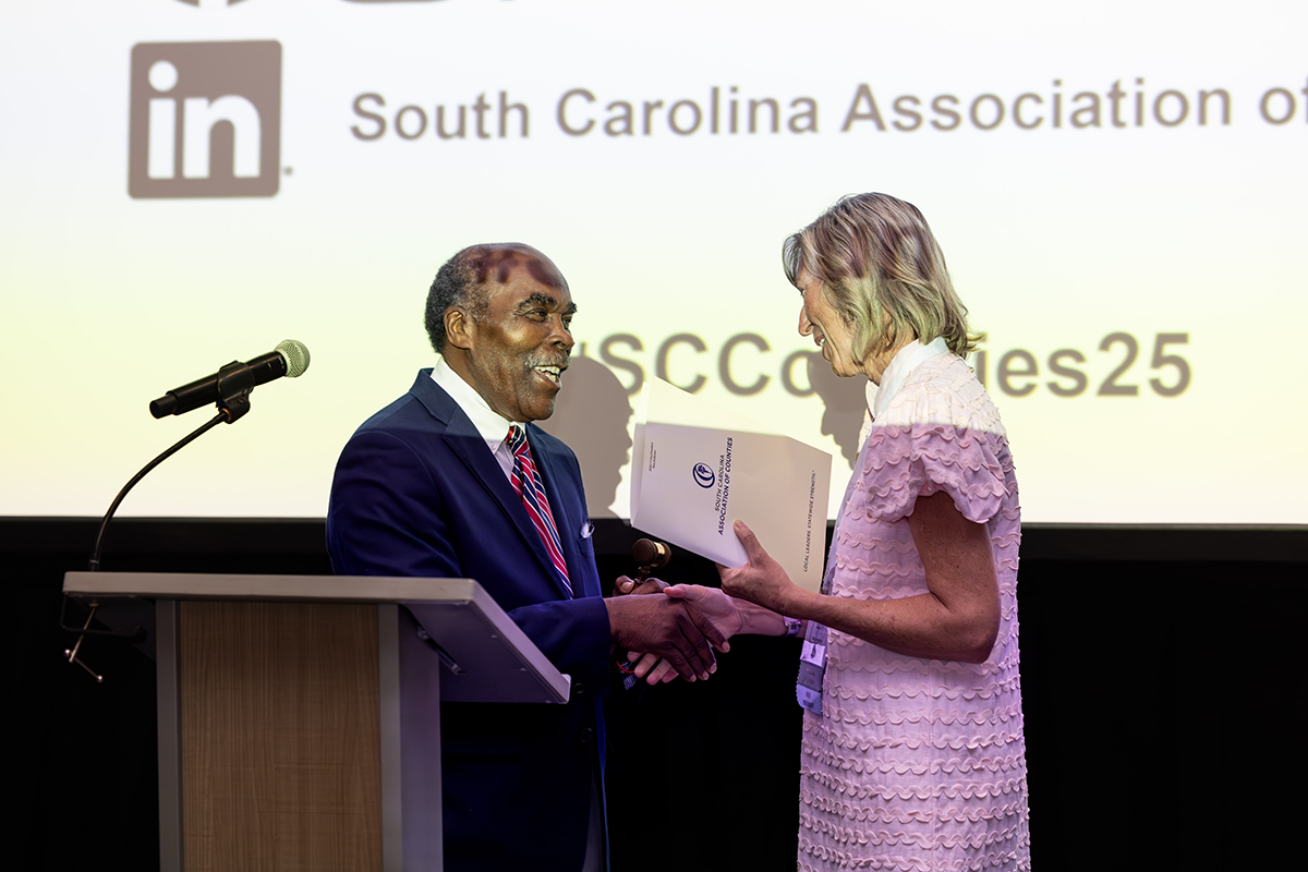 Outgoing SCAC President Bill Robinson passes the gavel to 2025-26 SCAC President Mary Anderson.